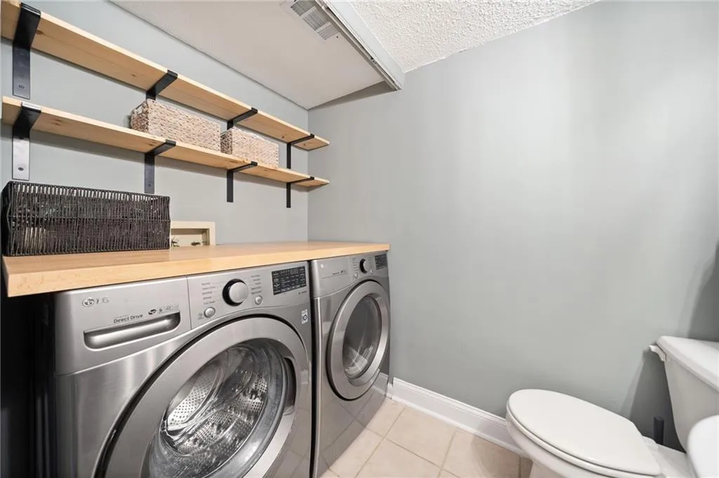 Washroom with light tile patterned floors, a textured ceiling, and separate washer and dryer