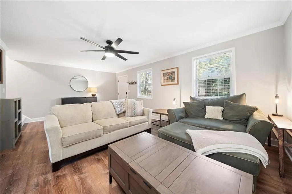 Living room featuring ornamental molding, ceiling fan, and dark wood-type flooring