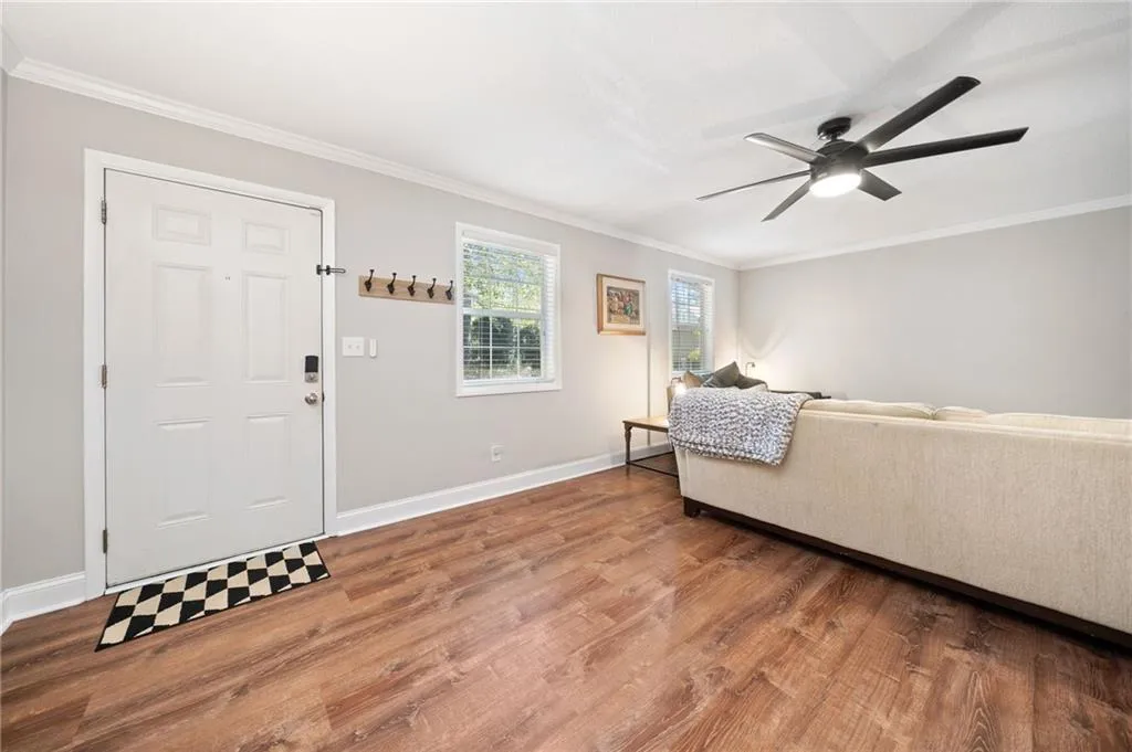 Living room featuring ceiling fan, wood-type flooring, and ornamental molding