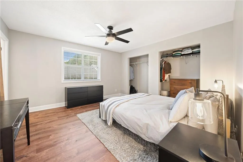 Bedroom featuring two closets, hardwood / wood-style flooring, and ceiling fan