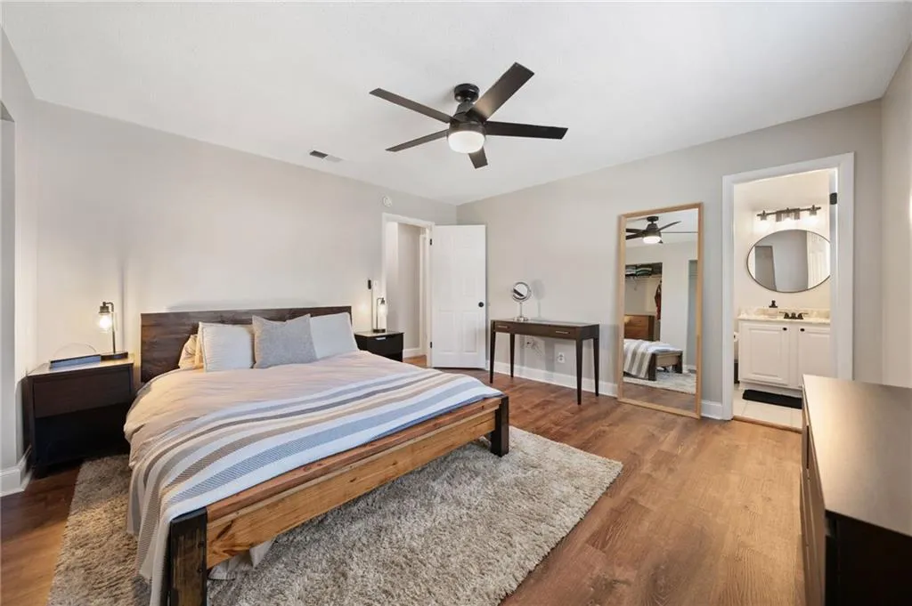 Bedroom featuring ensuite bath, ceiling fan, and wood-type flooring