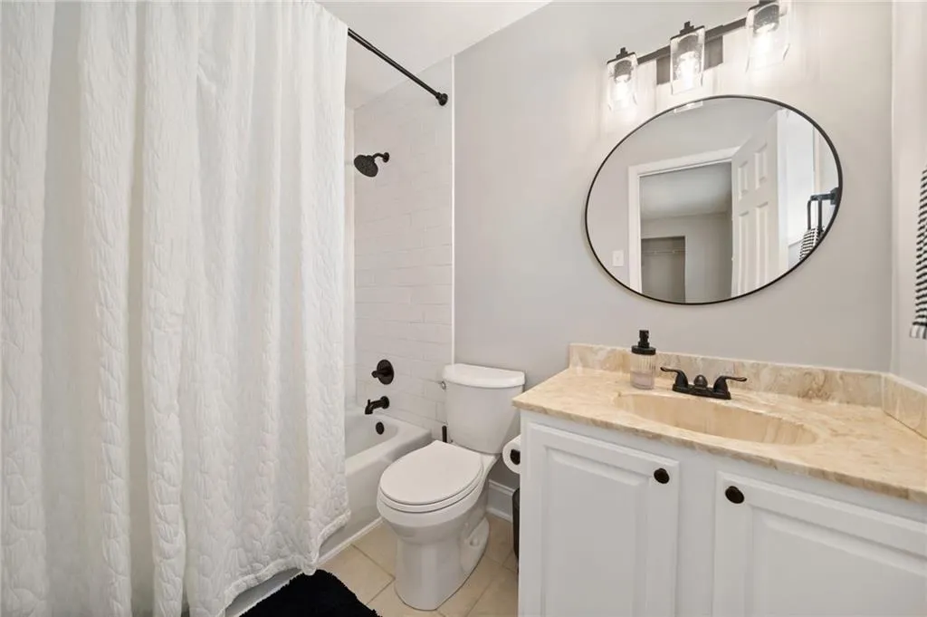 Full bathroom with tile patterned floors, vanity, shower / bath combination with curtain, and toilet