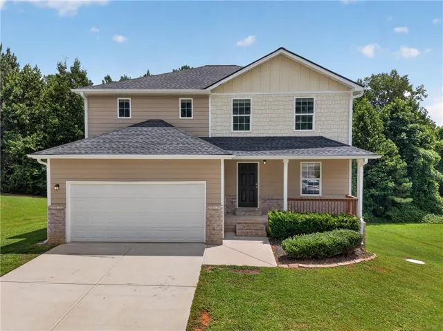 Two-story residence featuring a covered front porch, attached two-car garage, and a concrete driveway