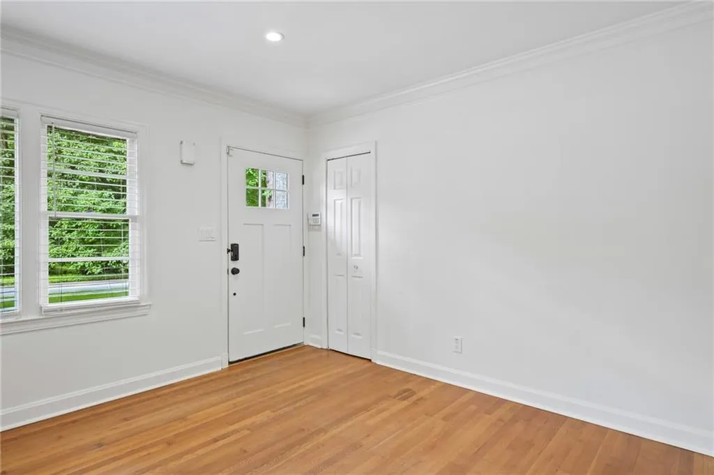 Entryway featuring wood-finish flooring, white walls, and crown molding