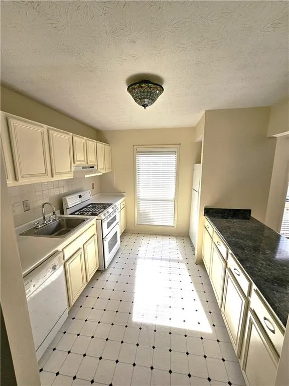Kitchen with sink, white appliances, light tile flooring