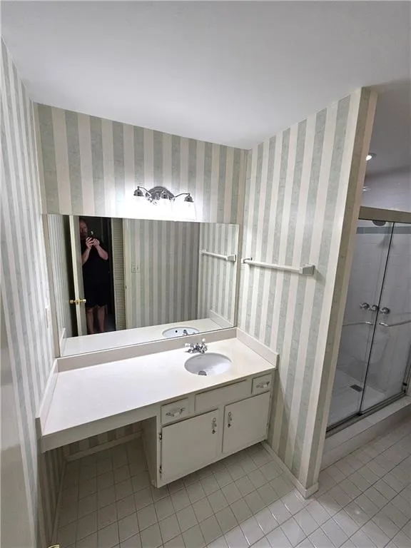 Bathroom with vanity, tile floors, and a shower with door