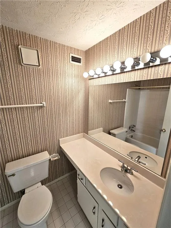 Bathroom with vanity with extensive cabinet space, tile flooring, and toilet