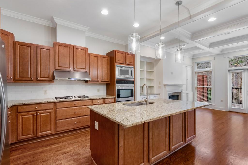 The spacious kitchen boasts a large island, stone countertops, ample storage, and stainless steel appliances.