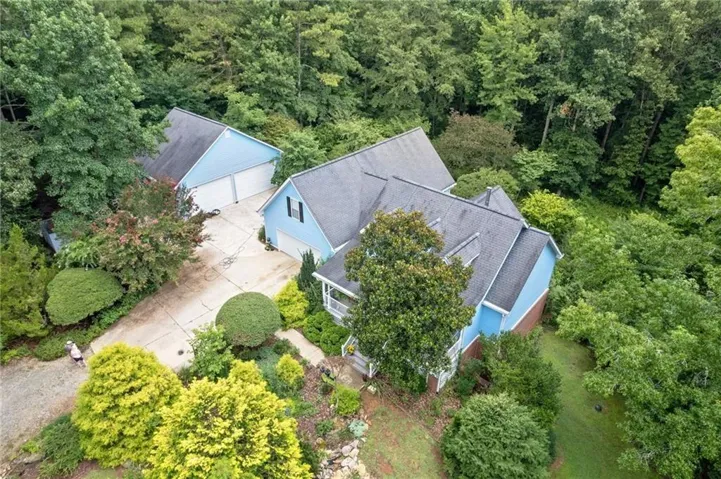 Main residence with a detached garage, both featuring light blue siding and dark shingle roofing