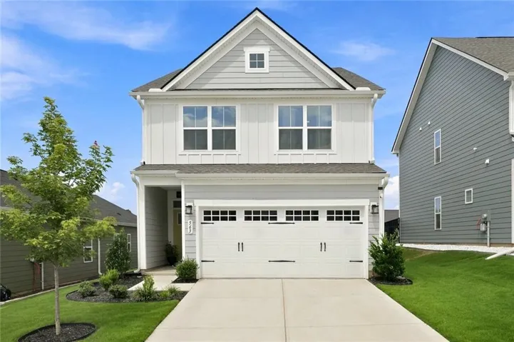 Two-story residence featuring light gray siding with white board and batten accents, a two-car garage, and a concrete driveway