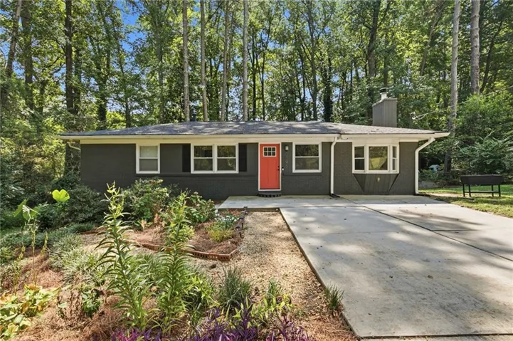 Charcoal exterior with white trim, a vibrant orange front door, a multi-pane bay window, and a concrete driveway