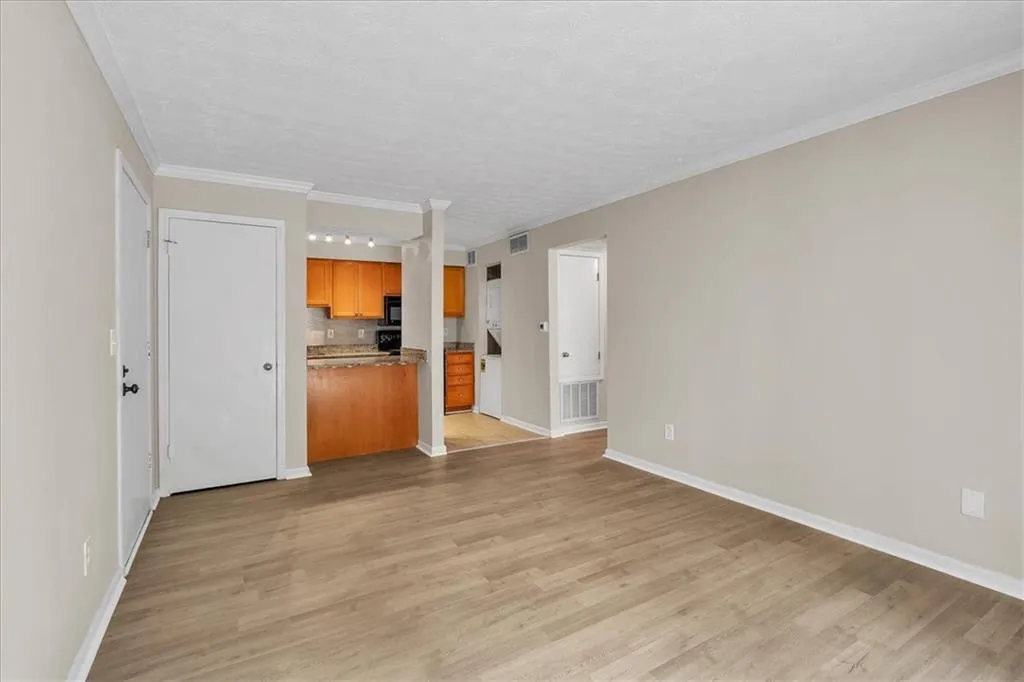 Unfurnished living room featuring light wood-type flooring, crown molding, and a textured ceiling