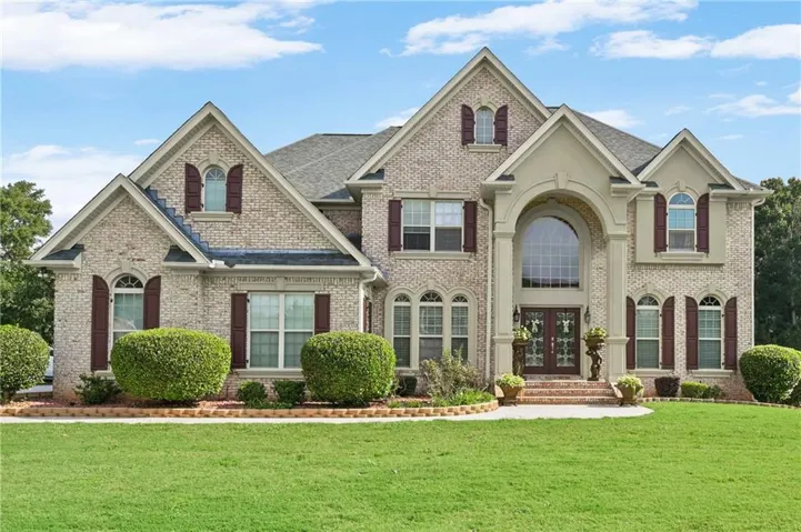Brick exterior with decorative shutters, arched window accents, gabled rooflines, and a prominent arched entryway