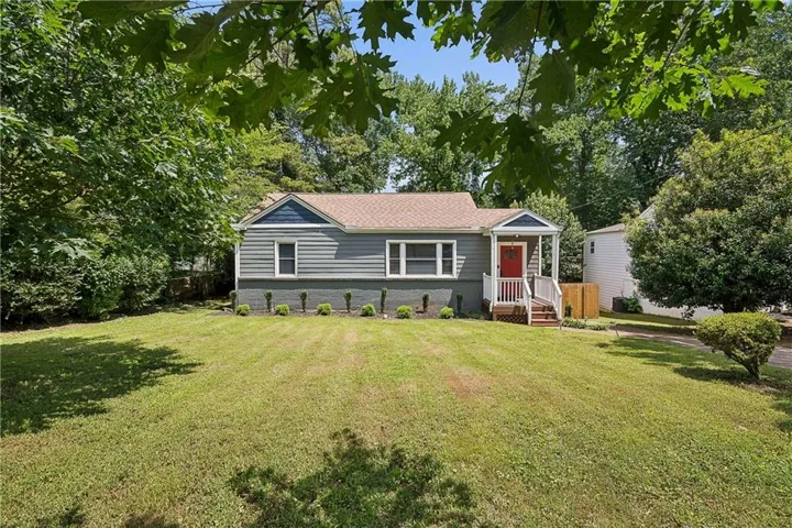 Ranch-style residence featuring grey siding, a contrasting red front door, and a covered porch with white railings