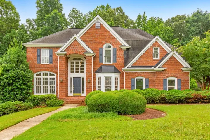 Traditional brick exterior featuring a prominent two-story entry with a dark-paneled door