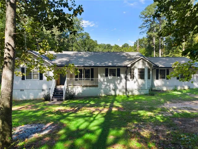 Single-story residence featuring a covered front porch, exterior steps with white railing, a gabled entry, and multiple windows with dark shutters