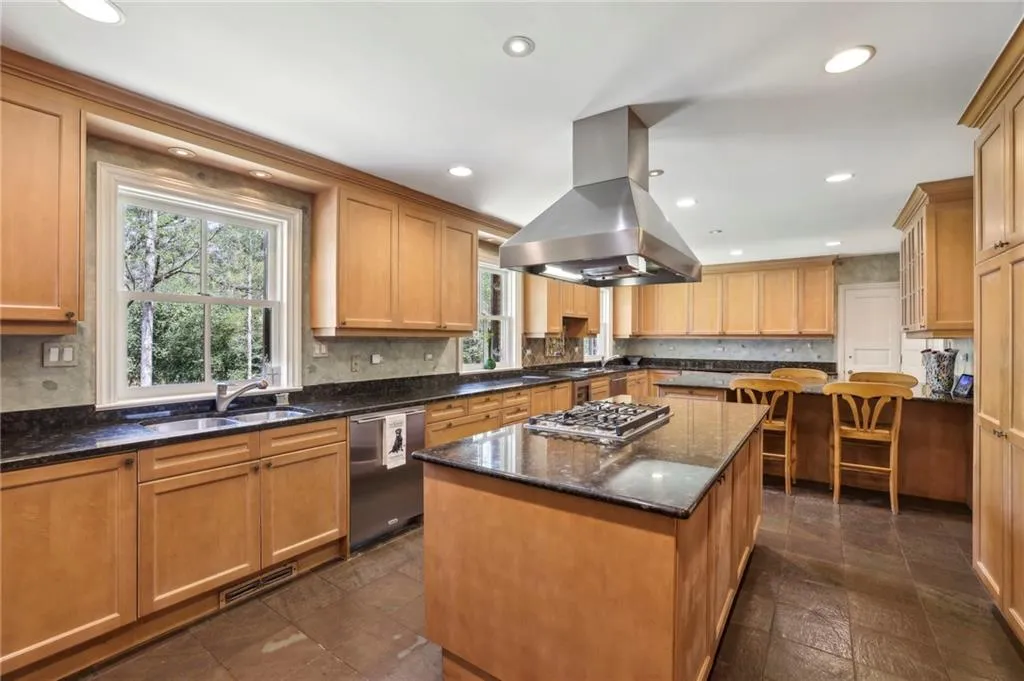 Kitchen with island range hood, a kitchen island, a sink, visible vents, and appliances with stainless steel finishes