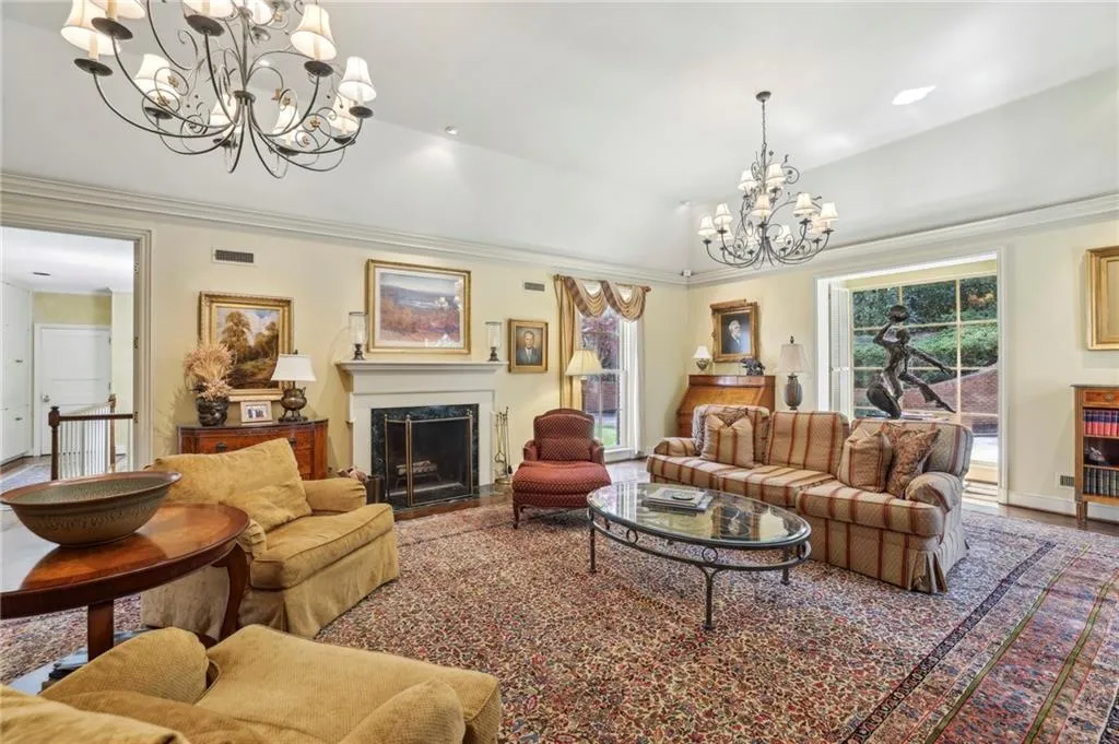 Living room with ornamental molding, a high end fireplace, and an inviting chandelier