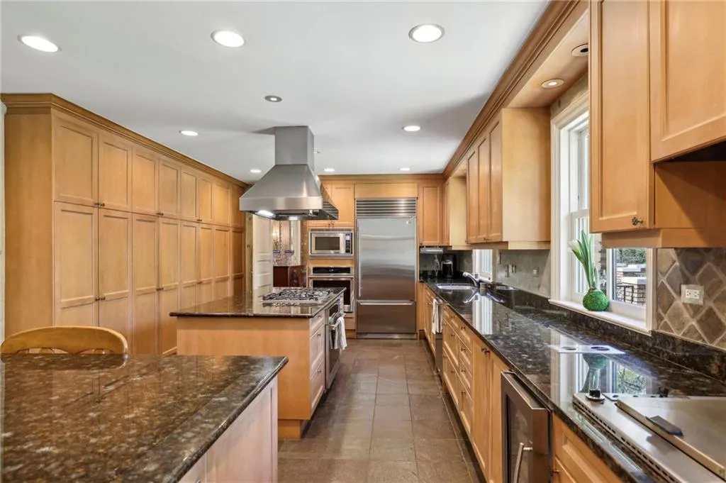 Kitchen featuring island exhaust hood, wine cooler, a kitchen island, built in appliances, and backsplash