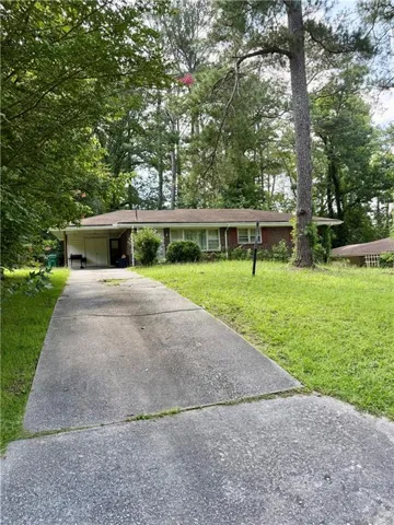 Brick exterior residence featuring a front yard with mature trees