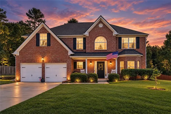 Brick exterior with dark shutters, dual garage doors, and a concrete driveway