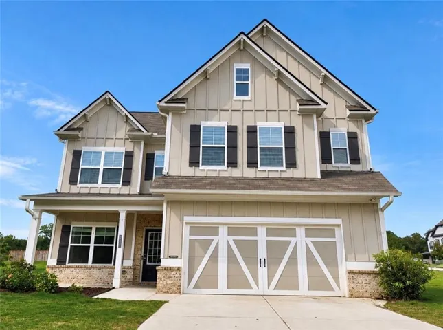 Two-story exterior with board and batten siding, stone accents, and a covered front porch