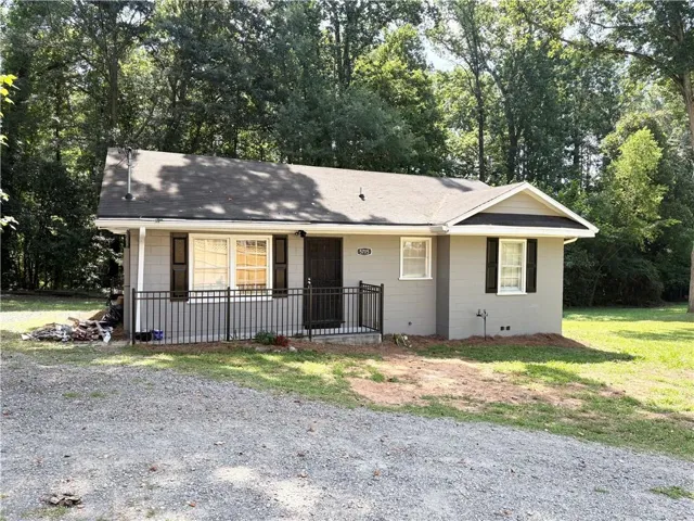 Light gray exterior siding with white trim, black shutters, and a dark asphalt shingle roof