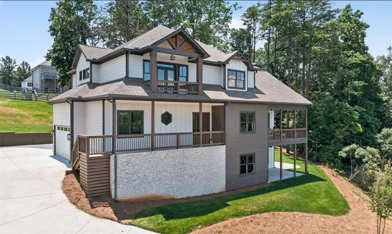 Craftsman-style exterior featuring white siding, brown trim, a covered front porch, an upper-level balcony, and an attached garage with a concrete driveway