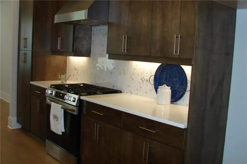 Kitchen featuring gas stove, tasteful backsplash, wood finish cabinets, and wood-style floors