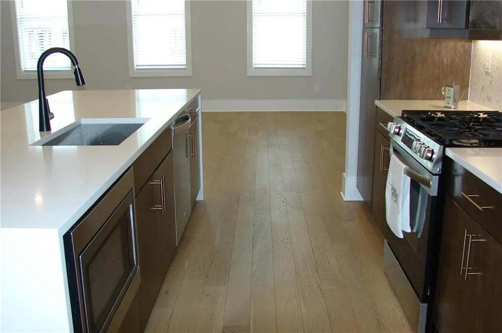 Kitchen featuring stainless steel appliances, light wood finished floors, and light stone countertops