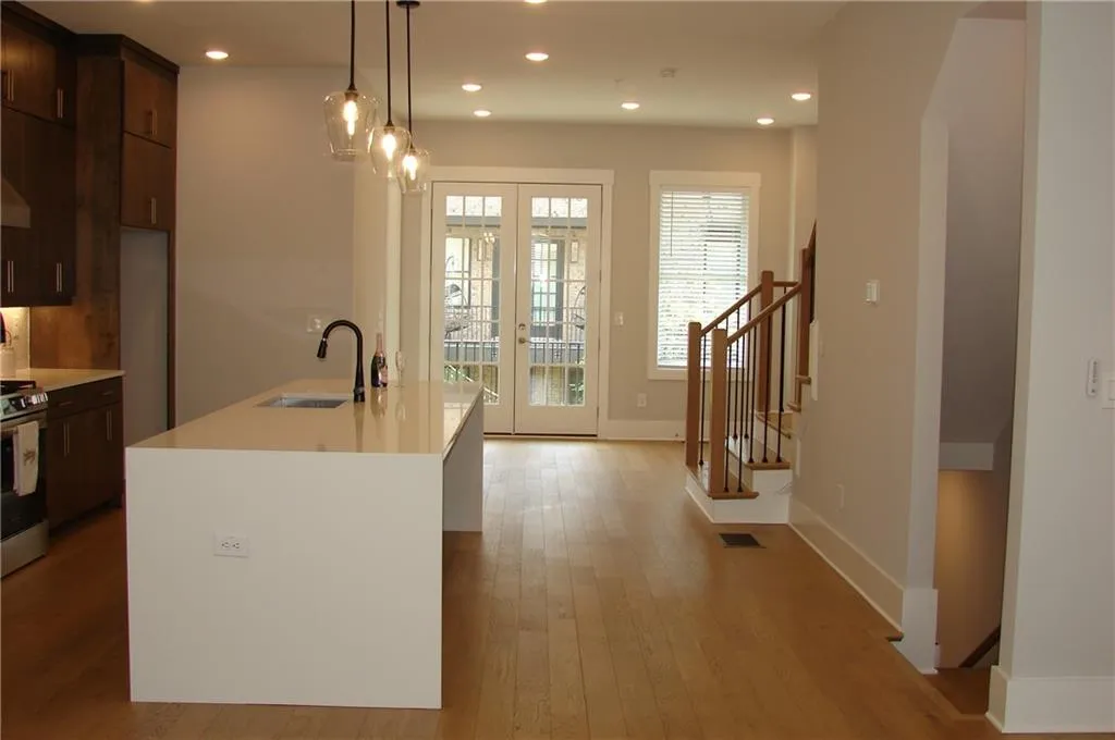 Kitchen with french doors, light wood-type flooring, pendant lighting, stainless steel range, and dark wood finish cabinetry