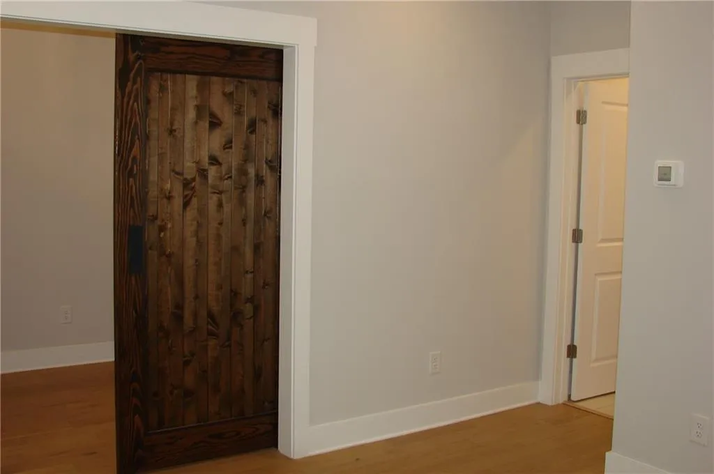 Lower level 3rd bedroom featuring light wood finished floors with a view of the barn door
