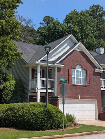 Brick and siding exterior featuring white garage door, upper-level balcony, and arched window