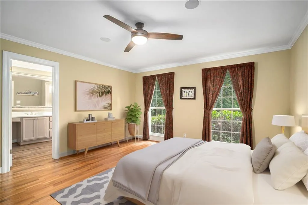 Bedroom with crown molding, light hardwood / wood-style flooring, ensuite bathroom, and ceiling fan Virtually Staged