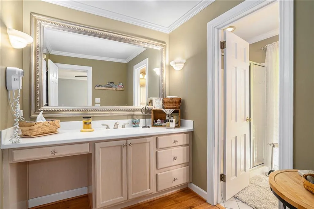 Bathroom featuring a shower with shower curtain, hardwood / wood-style floors, vanity, and ornamental molding