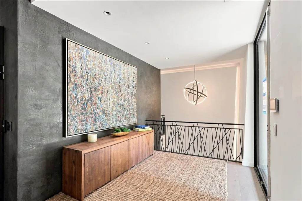 Textured wall finish, recessed ceiling lighting, light wood-finish flooring, contemporary railing design, and a modern spherical light fixture