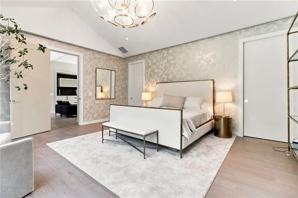 Vaulted ceiling, wood-finish flooring, accent wall with patterned wallpaper, recessed lighting, and a modern chandelier