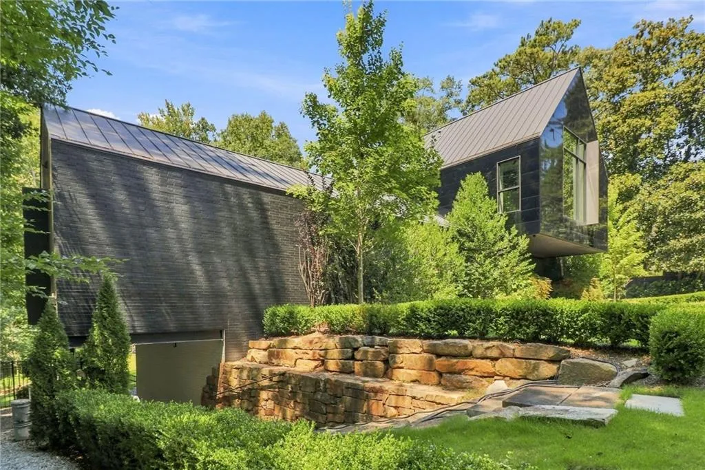 Modern architectural design featuring a prominent angled metal roof, dark textured siding, and large reflective windows