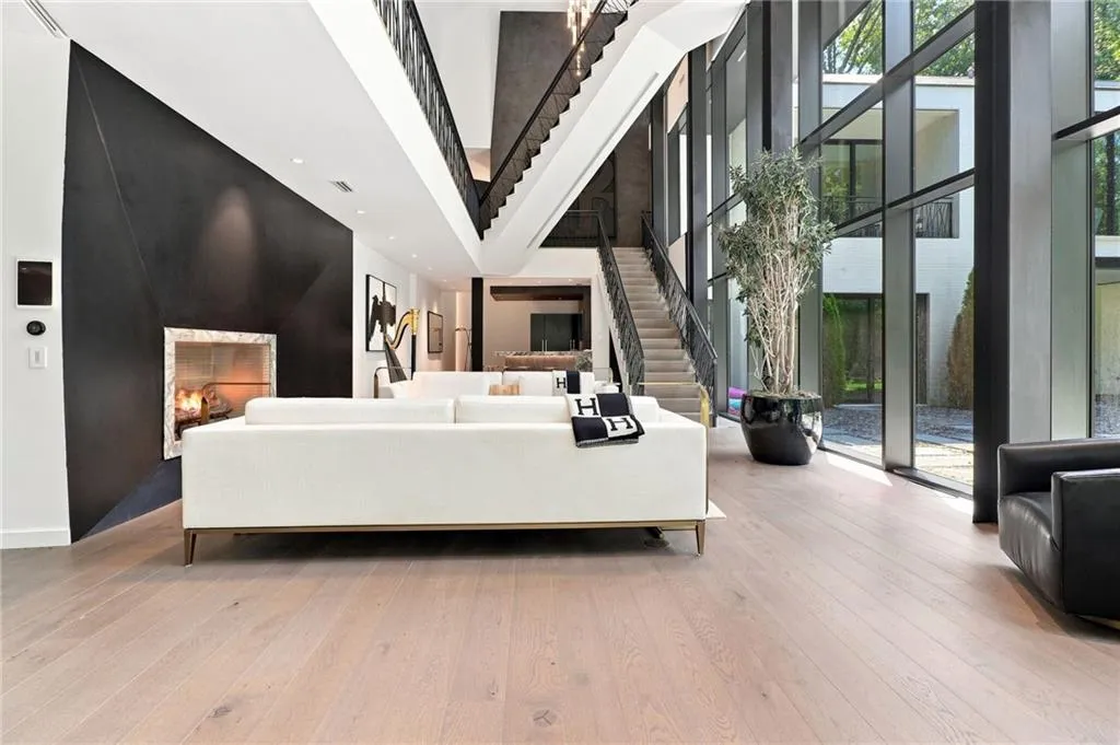 Expansive living space featuring light wood-finish flooring, a contemporary fireplace with a geometric surround, and a striking black accent wall
