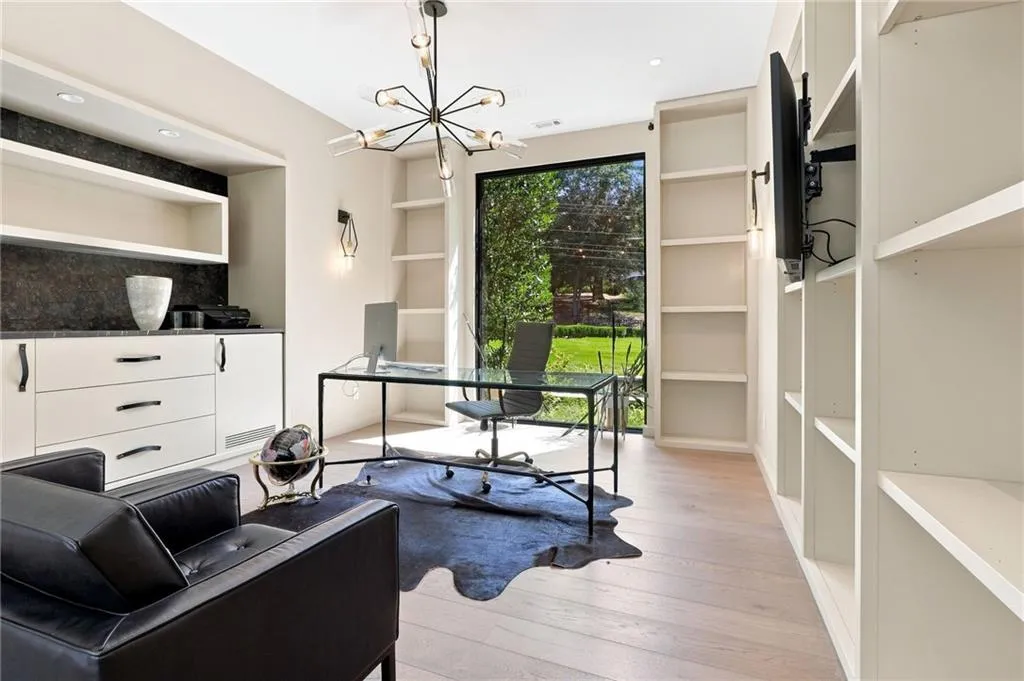 Built-in cabinetry with dark stone countertop, expansive built-in shelving, large picture window, and wood-finish flooring