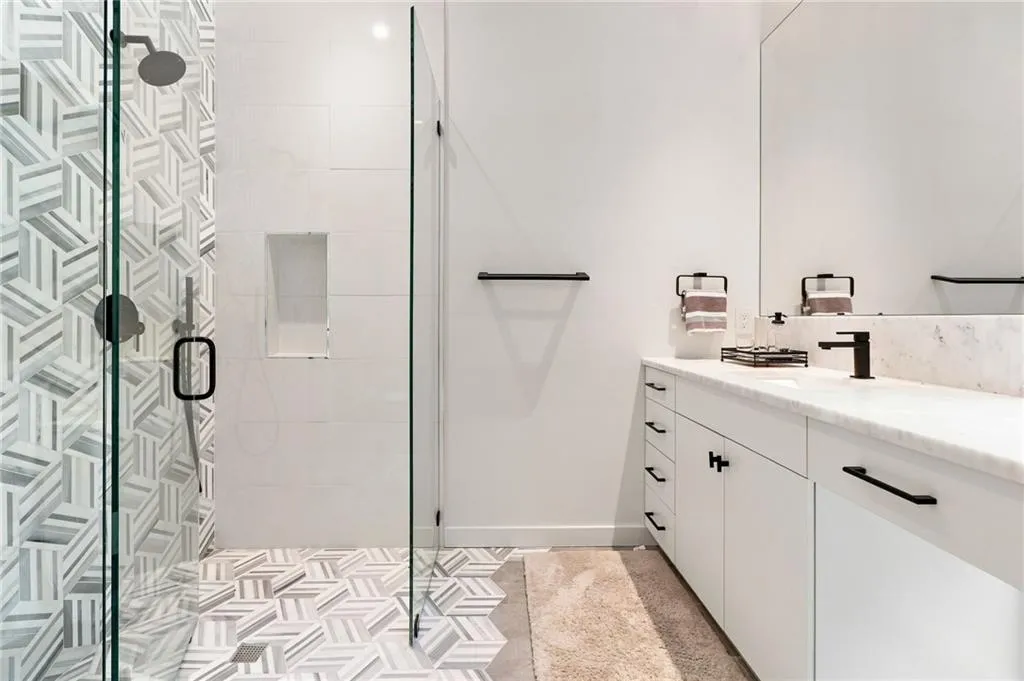 Glass-enclosed shower with geometric tile accents and a built-in niche