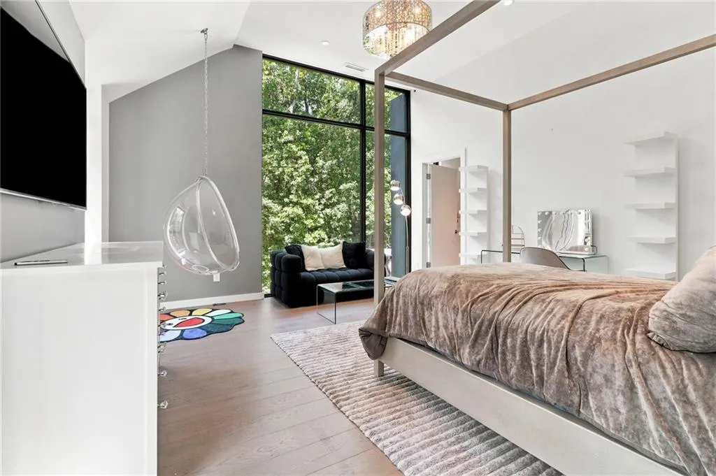 Vaulted ceilings with an exposed beam, expansive floor-to-ceiling windows, wood-finish flooring, and built-in wall shelving