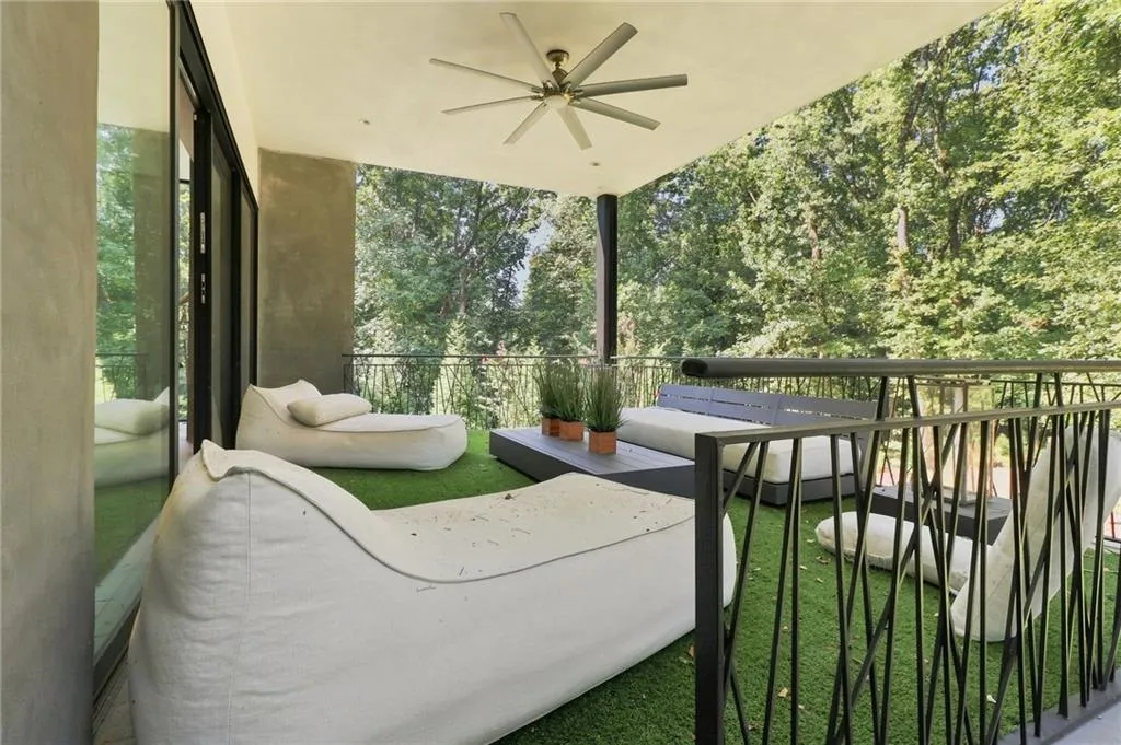 Covered balcony featuring a ceiling fan, black iron railing, and artificial turf flooring