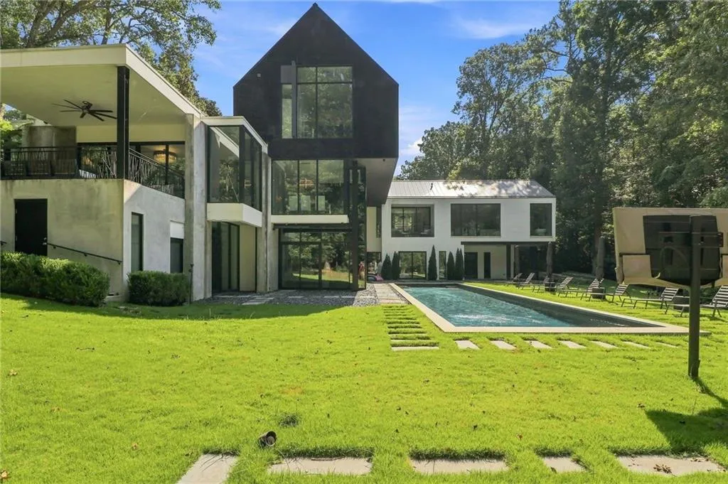 Modern architectural design featuring a rectangular swimming pool, expansive green lawn, and mature trees