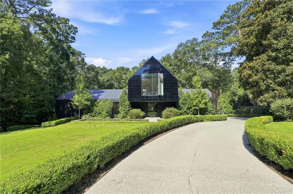 Modern residence with a black facade and a prominent peaked roofline, featuring a large vertical window