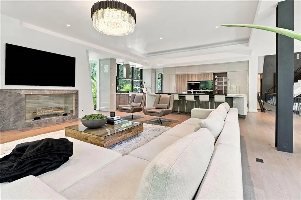Recessed lighting, wood-finish flooring, and a linear fireplace with a stone surround
