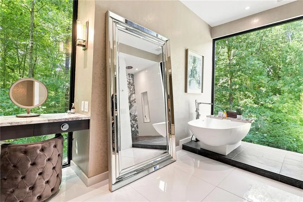 Freestanding soaking tub with a floor-mounted faucet, vanity with a stone countertop, large format windows, and white tile flooring