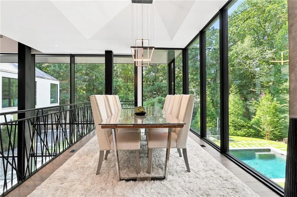 Expansive floor-to-ceiling windows, sculptural ceiling design, contemporary chandelier, custom metal railing, and a visible pool