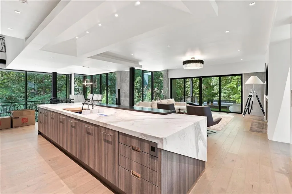 Expansive open-concept space featuring a large central island with integrated sink, wood-finish cabinetry, and light-toned flooring