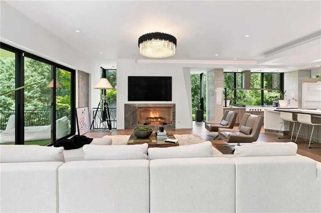 Spacious interior featuring a contemporary chandelier, built-in fireplace with a stone surround, wood-finish flooring, and expansive sliding glass doors